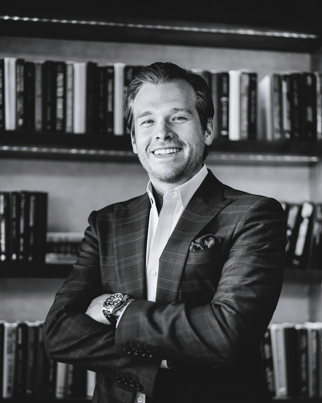 Studio portrait of a Dutch middle-aged male author in a tweed jacket in front of bookshelves